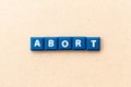 Tile letter in word abort on wood background