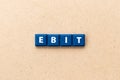 Tile letter in word EBIT Abbreviation of Earnings Before Interest and Taxes on wood background