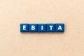 Tile letter in word EBITA abbreviation of earnings before interest, taxes and amortization on wood background