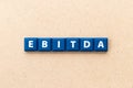 Tile letter in word EBITDA abbreviation of earnings before interest, taxes, depreciation and amortization on wood background