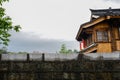 Tile-roofed timberwork building behind stone wall after rain in