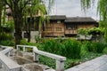 Tile-roofed wooden houses behind wayside garden in cloudy spring