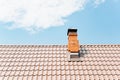 Tiled roof of a house with a brick chimney against a blue cloudy sky during the day. Exterior of a country house