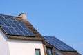 The tiled roof of the house with a chimney is covered with solar panels. Blue sky Royalty Free Stock Photo