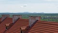 tiled roof and old chimneys part of the castle building on the background of the horizon mountains and lonely clouds