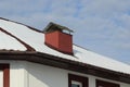 Tiled roof of a private house under white snow with a red metal chimney on a winter street Royalty Free Stock Photo