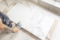 Tiler cutting a floor tile with a portable angle grinder. Craftsman hands using electric saw on marble ceramic tiles. Bathroom