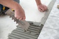 Tiler laying the ceramic tile on the floor. Professional worker makes renovation. Construction. Royalty Free Stock Photo