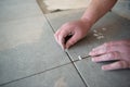 Tiler laying the ceramic tile on the floor. Professional worker makes renovation. Construction. Royalty Free Stock Photo