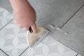 Tiler laying the ceramic tile on the floor. Professional worker makes renovation. Construction. Hands of the tiler