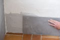 The tiler lays a ceramic tile on the wall