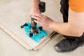 A tiler uses a caliper with a suction cup to drill holes in the tile
