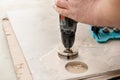 A tiler is using a diamond crown to drill holes in the tile