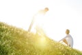 Tilt image of young couple spreading picnic blanket on grass during sunny day