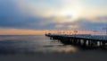 Tilt Shift photograph of a large wooden pier in the sea against a sunrise. Beautiful seascape. Royalty Free Stock Photo