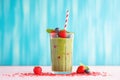 tilted angle: spinach berry smoothie in a tall glass, against a brightly colored background
