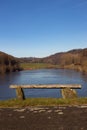 Tilted empty old bench on a hill overlooking a frozen lake