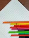 Tilted empty white notebook with lines and colorful pens on top for taking notes on the lectures and better organization