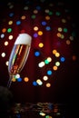 Tilted glass with bubbling champagne on festive background