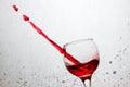 Tilted glass of red wine pierced a stream of alcoholic beverage Royalty Free Stock Photo