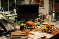 tilted view of a messy office desk with a halfeaten burger