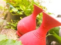 A tilted view of red colored earthen pots placed in a garden