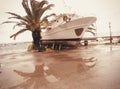 Tilted vintage look photo of a palm tree and decommissioned large fishing boat