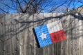 Tilted wooden Texas flag on wood slat fence on perimeter of property.