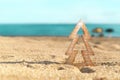 Timber Christmas tree with star sits in pristine white sand with idyllic beach background. A summer Christmas