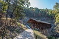 Timber frame-covered bridge surrounded by rocks, trees and a waterfall. Royalty Free Stock Photo