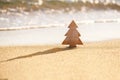 Timber wooden Christmas tree on a sand on the tropical beach near ocean, summer Christmas and winter holyday concept Royalty Free Stock Photo