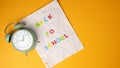 Time for back-to-school concept with clock and notebook paper on yellow background Royalty Free Stock Photo