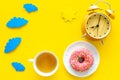 Time for breakfast concept. Tea, donut near alarm clock, sun and clouds cutout on yellow background top view copy space Royalty Free Stock Photo