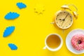 Time for breakfast concept. Tea, donut near alarm clock, sun and clouds cutout on yellow background top view copy space Royalty Free Stock Photo