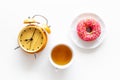 Time for breakfast concept. Tea, donut near alarm clock on white background top view Royalty Free Stock Photo