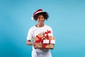 Time for celebration. Overjoyed black guy in santa hat holding stack of present boxes over blue background Royalty Free Stock Photo