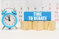Against the background of the calendar is an alarm clock, cubes and a blue block with the inscription - Time to Debate Royalty Free Stock Photo