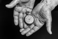 Time concept. Vintage clock in old senior wrinkled male hands on black background