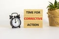 Time for corrective action symbol. Blocks with words time for corrective action. Black alarm clock, house plant. Beautiful white