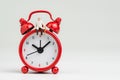 Time counting down for retirement concept, miniature happy senior old man sitting on big red alarm clock on white background with