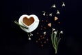 Time for a cup of coffee: a cup of coffee in the shape of a heart, snowdrops around, scattered beans everywhere, two sugar cubes,