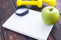 Time for diet slimming weight loss concept. Sport fitness, apple, sneakers, bottle of water and yellow weights on dark wooden back Royalty Free Stock Photo