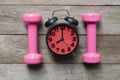 Time for exercising sport equipment, alarm clock with dumbbell on wooden table background Royalty Free Stock Photo