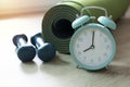 Time for exercising sport equipment, dumbbell, alarm clock with green yoga mat background Royalty Free Stock Photo