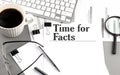 TIME for FACTS text on a paper with magnifier, coffee and keyboard on grey background