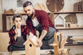 Father and his son working together in a wooden workshop, building a birdhouse