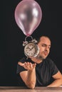 Time flies concept - picture of a man looking at the camera while placing his hand underneath an old metal clock Royalty Free Stock Photo