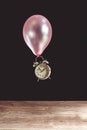 Time flies concept - picture of an old metal clock attached to a pink balloon Royalty Free Stock Photo