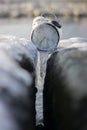 Time frozen alarm clock in ice on the beach between two rocks