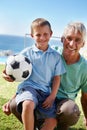 Time for a game of soccer. a young boy sitting on his grandfathers knee while holding a soccer ball. Royalty Free Stock Photo